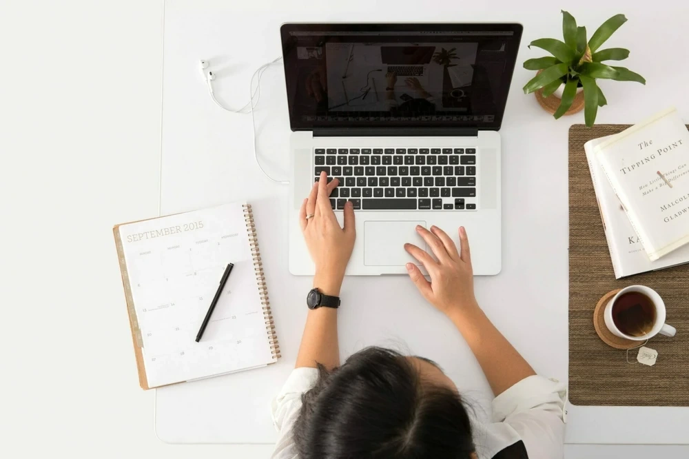Topview image featureing a female designer, editing photos on her laptop