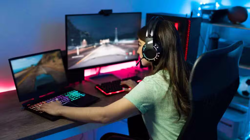 Girl playing games on gaming computer and laptop