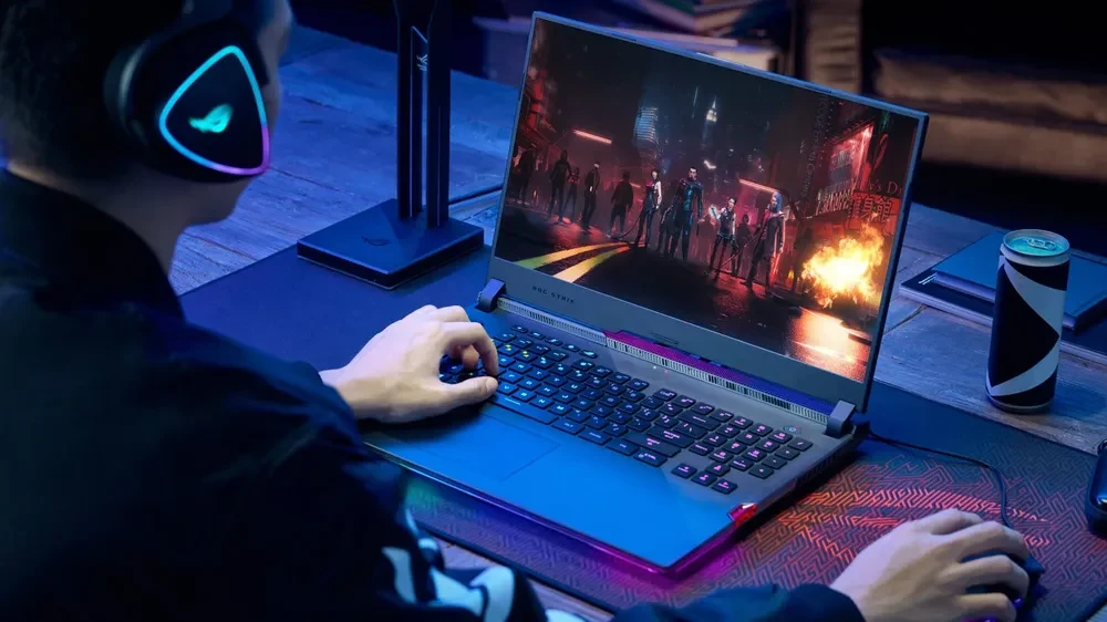 The back of a man playing games on a black laptop, displaying a mouse and keypad