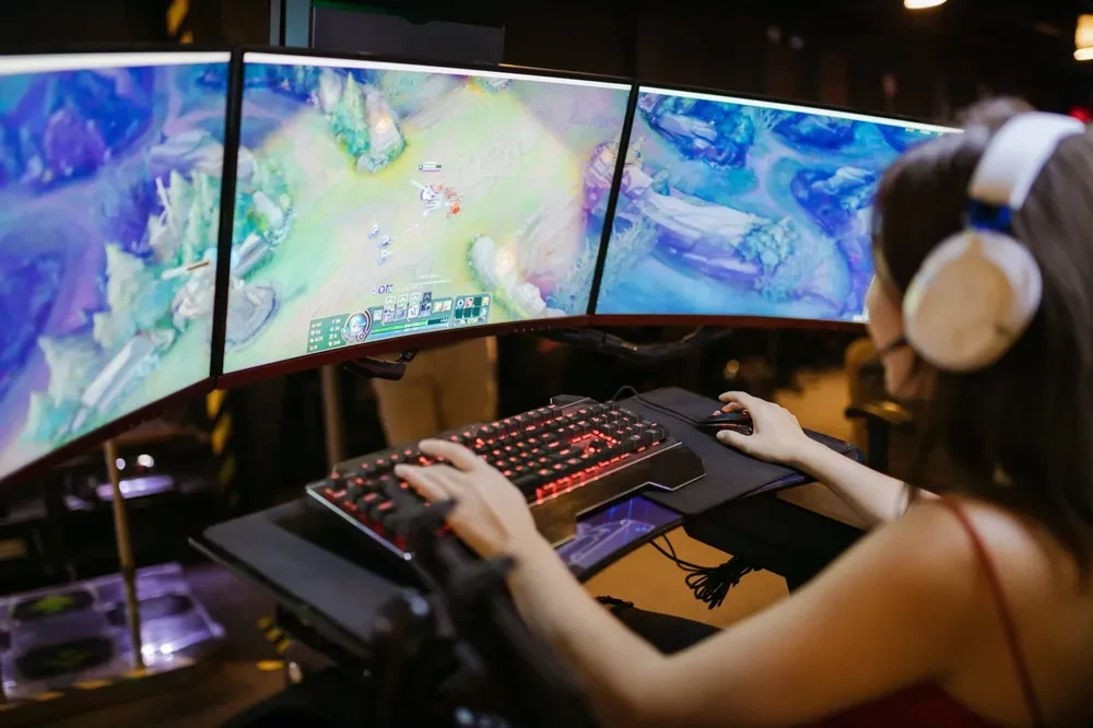 Girl playing online game with 3 splitting monitors