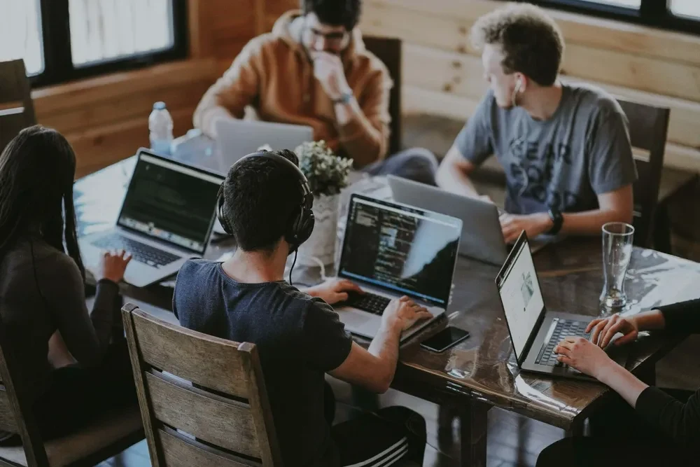 5 programmers sitting at one table with all their laptops